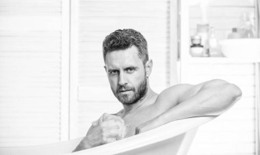 Adam kaslı vücudu süngerle yıkıyor. Küvette çıplak maço. Maço, çekici, çıplak adam. Banyodaki seksi adam. Köpüğü dikkatlice suyla yıka. Seks ve rahatlama konsepti. Toplam rahatlama