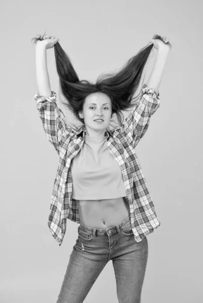 Sexy vrouw met mode look in casual stijl houden lang gezond haar gele achtergrond, haarverzorging — Stockfoto