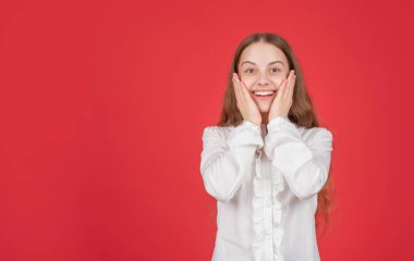 Şaşırmış çocuk yüz ifadesi kırmızı arkaplan fotokopi alanı ve flaş satış konularında olumlu duygularını ifade eder.