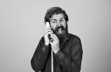 İletişim. Sakallı adam kırmızı gömlek giyer. Sıradan bir erkek telefonu. Sohbet konsepti. Adam sekreter ya da asistan retro telefonda konuşuyor. Telefonlu acımasız adam.