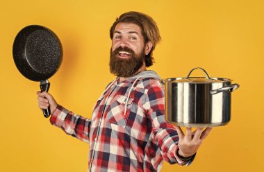 Tutkuyla yemek pişirmek. Profesyonel aşçı. Sakallı adam mutfak tepsisini tut. Tencereli vahşi hippi yemekleri. Hizmetçi koca, tencerede yemek yapıyor. Kareli gömlekli olgun bir aşçı. Evde yemek hazırla.