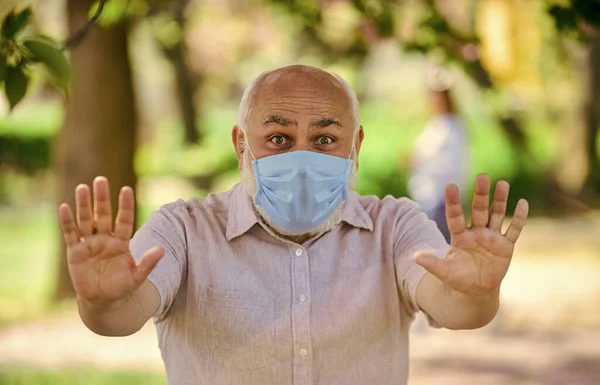 Hou afstand. beperkt openbaar park. park is gesloten voor quarantaine vanwege coronavirus. senior man met masker. lentebloesem boom in het park. coronavirus covid19. lentegenot — Stockfoto