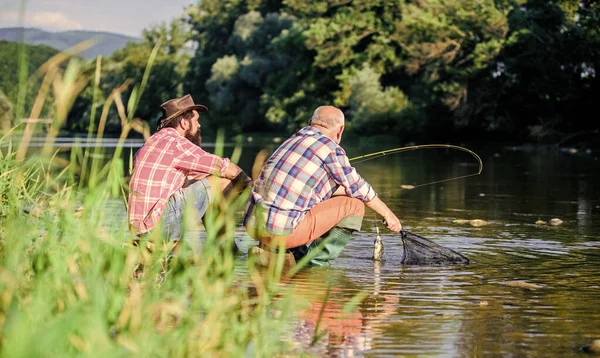 Dos amigos pescando juntos. pesca de caza mayor. relajarse en la naturaleza. feliz amistad de pescadores. padre jubilado e hijo barbudo maduro. pasatiempo peces mosca de los hombres. pesca de jubilación. Lo hemos cogido. — Foto de Stock