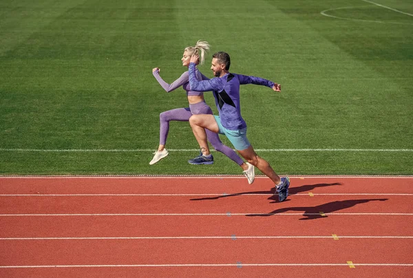 Homem atlético e mulher sexy competir em sprint. Treinador masculino e feminino na pista de corrida do estádio. estilo de vida saudável. velocidade da maratona. casal esporte correr rápido para ganhar. molinetes fitness de sucesso — Fotografia de Stock