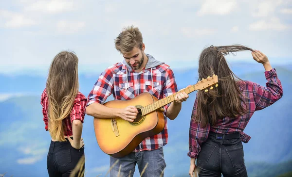 Μόνο φίλοι και κιθάρα. Οι άνθρωποι χαλαρώνουν στην κορυφή του βουνού, ενώ όμορφος άντρας παίζει κιθάρα. Πεζοπορία ψυχαγωγία. Ειρηνικό μέρος. Μελωδία της φύσης. Παράδοση πεζοπορίας. Φίλοι πεζοπορία με μουσική — Φωτογραφία Αρχείου