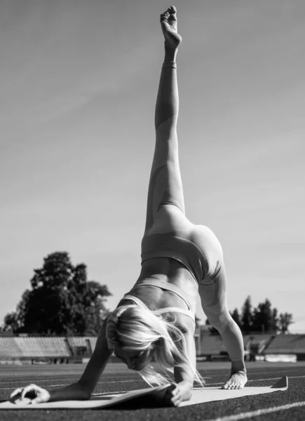 Flexible woman stretching on stadium in sportswear, pilates — Stock Photo, Image