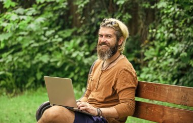 Çevik iş. Sakallı adam park doğasında bankta oturuyor. Çalış ve rahatla. Temiz hava. Gezici internet. İstediğin yerde çalışabilirsin. İnternetten alışveriş. İnternette çalışıyorum. Hipster parkta çalışmaktan esinlendi