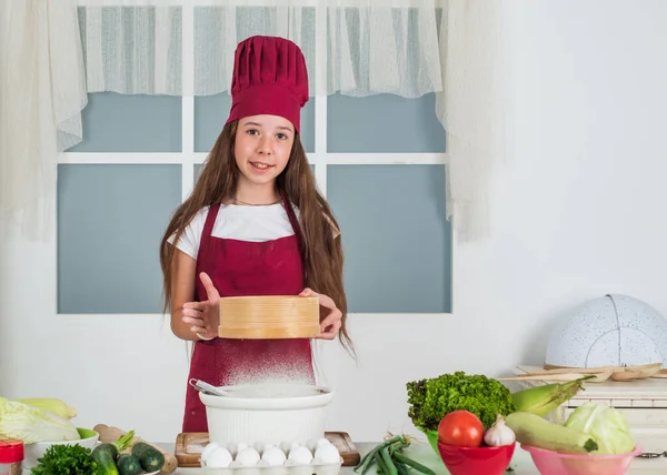 Nourriture avec passion. petite aide sur la cuisine. culinaire et gastronomique. bonne enfance. enfant heureux porter uniforme de cuisinier. chef fille en chapeau et tablier. cuisine pour enfants dans la cuisine. choisir une carrière — Photo