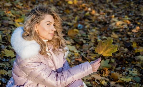 Csinos nő hosszú göndör szőke haj viselni őszi puffer kabát erdőben lehullott levelek, szépség — Stock Fotó