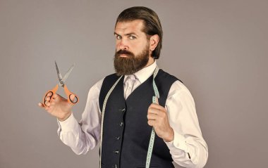 Kendine güvenen bir terzi. Model için özel dikim takım elbise. İş gömleği mağazada mezura ve makasla dikiliyor. Beyaz gömlekli yakışıklı terzi. Antika mobilyalarla muhteşem bir atölye.