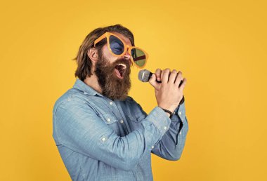 Komik parti gözlüklü olgun sakallı adam şarkı söyler. Mikrofonlu vahşi erkek hippi. vokal okulu. En sevdiği müzik tarzı. Müzik konsepti. Oyuncu eğleniyor.