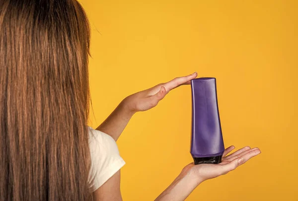 Kid girl with long straight hair hold conditioner shampoo or gel bottle, hair health — Stock Photo, Image