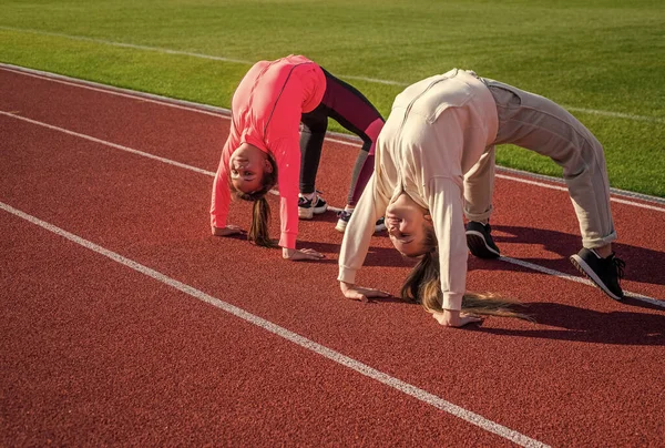 Chicas flexibles gimnastas de pie en posición de cangrejo en pista de atletismo, flexibilidad — Foto de Stock