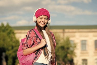 Modern çocukların şarkısı. Mutlu kız açık havada kulaklık takıyor. Küçük çocuk müzik dinler. Hi-Fi ses sistemi. Dijital ses. Modern teknoloji. Eğlence ve eğlence. Modern yaşam tarzı