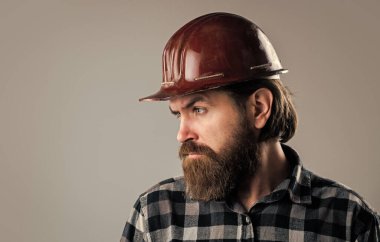 Kareli gömlekli sakallı erkek hippi ve işçi kaskı, alet edevat dükkanı.