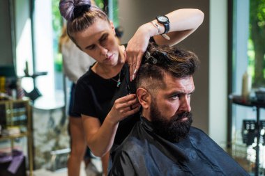 Olgun, sakallı bir erkeğin berber dükkanındaki kuaföre sakal tıraşı olması, yeni bir saç modeli tasarlaması.