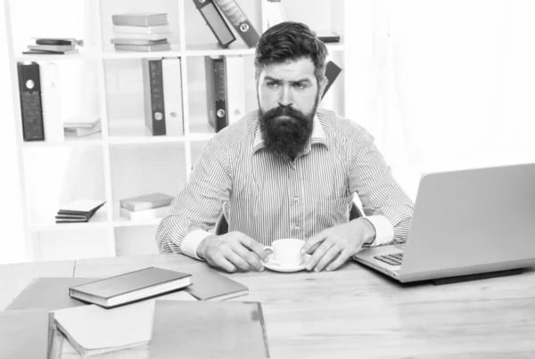 Brutaler Hipster mit ernstem Blick trinkt Kaffee am Agenten-Desktop im modernen Büro — Stockfoto