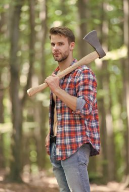 Ekose gömlekli sakallı bir adam. Kot pantolonlu. Büyük bir baltası var.