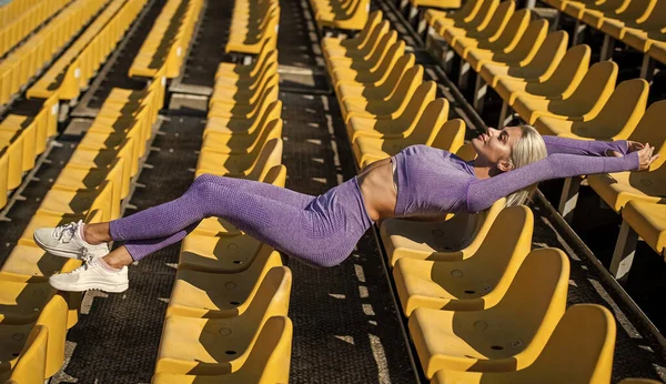 Vrouw met sexy fitness lichaam in sportkleding ontspannen op het stadion, fit lichaam — Stockfoto