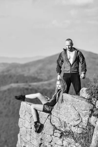 On edge of world. Woman sit edge of cliff high mountains landscape background. Hiking peaceful moment. Tourist hiker girl and man relaxing. Couple hikers enjoy view. Hiking benefits. Hiking weekend