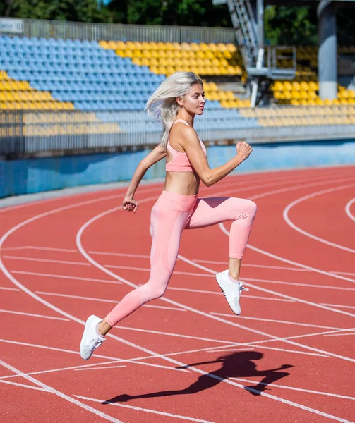 身强体壮的女运动员穿着运动服在体育场跑步 — 图库照片