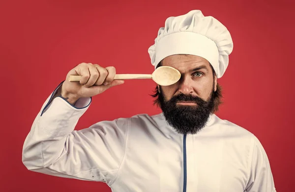 Mannelijke chef-kok in hoed met baard en snor op rode achtergrond gebruik houten keukengerei, koken — Stockfoto