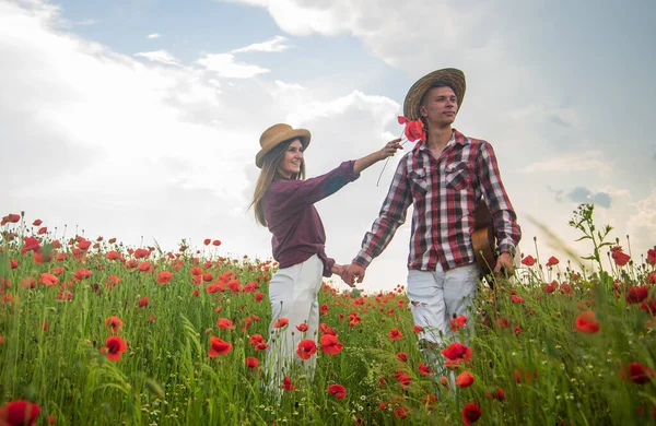 look there. couple in love. man with guitar and woman in poppy field.
