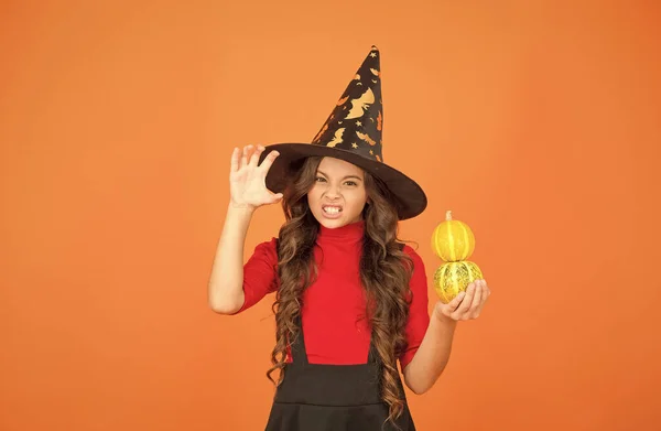 Enfant heureux avec des cheveux longs porter chapeau sorcière tenir citrouille pour Jack o lanterne à la célébration des vacances d'automne, nourriture traditionnelle halloween — Photo