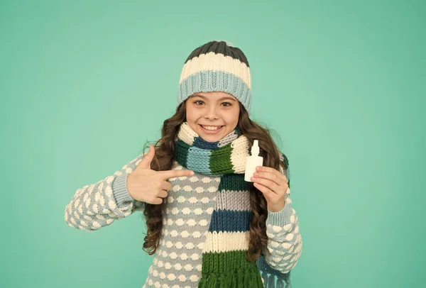 Menina bonita com polegar para cima em roupas quentes de malha usar spray nasal, tratamento vívido. — Fotografia de Stock