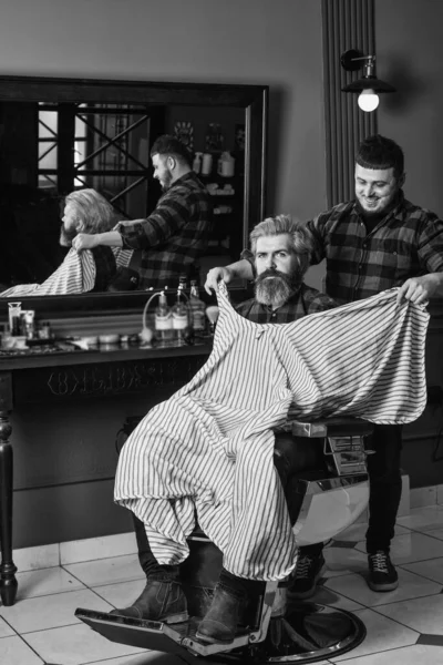 Barbeiro trabalha no penteado para barbearia homem barbudo fundo. Um cliente Hipster a cortar o cabelo. Barbeiro e cabeleireiro dedicam-se a torná-lo mais bonito pessoa. Barbeiro com tesoura e cliente — Fotografia de Stock