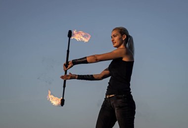 Enerji ve zarafet. Seksi kız alevli baton mavisi gökyüzünü çeviriyor. Ateş gösterisi. Sanat gösterisi ya da performans. Sopa çevirme. Tatil kutlaması. Gece partisi. Arzu ve tutku alevi