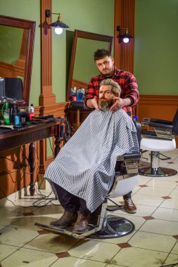 Yeni saç kesimi zamanı. Berber dükkanında saçını kesen sakallı bir hippi. Profesyonel kuaförlük işi. Yaşam tarzı. Usta berber saç stilini ve saç stilini kurutma makinesiyle yapıyor. Berber Dükkanı