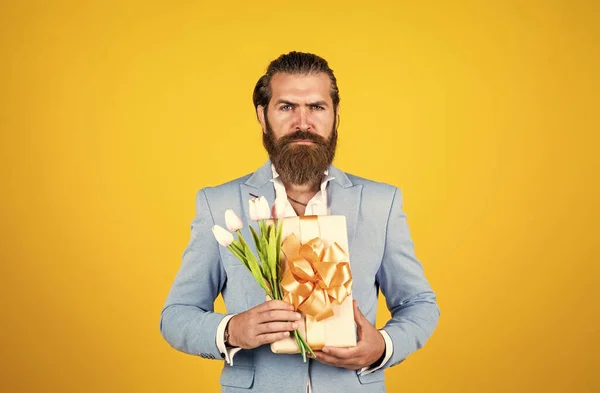 Être ma valentine. concept actuel de vacances. homme beau brutal avec boîte cadeau. Saint Valentin ou jour des femmes. masculinité et charisme. code vestimentaire officiel. barbu hipster tenir bouquet de fleurs de tulipe — Photo