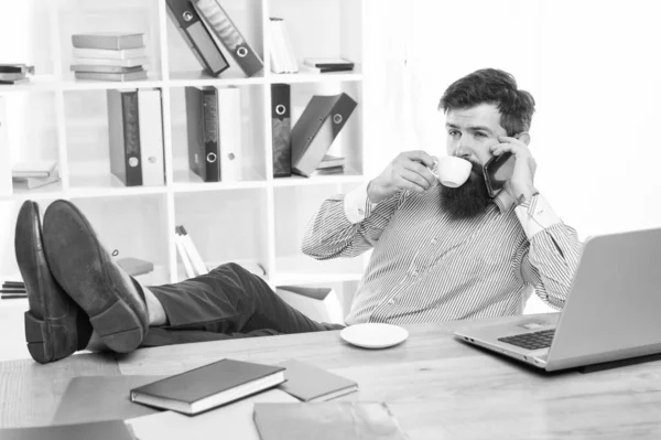 Деловой человек разговаривает по мобильному телефону, выпивая чашку чая в современном офисе, бизнесмен — стоковое фото