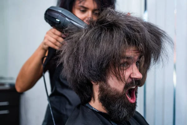Дути сухе волосся в перукарні жорстокого зрілого крику клієнта, перукар — стокове фото