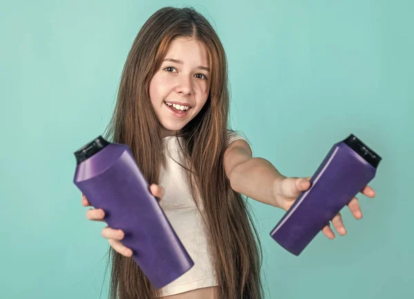 Menina alegre com cabelo liso longo segurar condicionador xampu ou garrafa de gel, higiene — Fotografia de Stock
