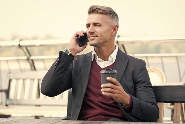 Suaviza tu día. Los empleados hablan por teléfono bebiendo café al aire libre. El hábito matutino. De buen humor. Hora del desayuno. Un adicto a la cafeína. Comunicación empresarial. Tecnología moderna — Foto de Stock