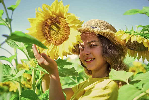 Retrato de niño feliz con hermoso girasol. niño alegre en sombrero de paja entre flores amarillas. niña en el campo de girasol de verano. Feliz día de los niños. felicidad infantil —  Fotos de Stock