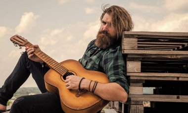 Müzik için mükemmel bir yer. Modern görünümlü sakallı, akustik gitarlı hippi. Bıyıklı vahşi yakışıklı adam gitar çalıyor. Olgun müzisyen ve şarkıcı. Sıradan stil gitarist.