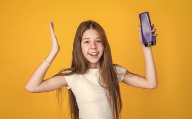 Uzun düz saçlı neşeli kız saç kremi şampuan ya da jöle şişesi, duş.