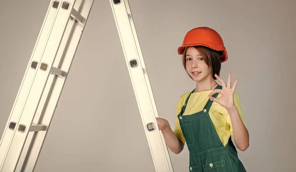 Meisje in helm speelt bouwer. bouwen en renoveren. Bouw van een kind. ingenieur tiener is bouwvakker. Internationale arbeidersdag. elektricien op trapladder — Stockfoto