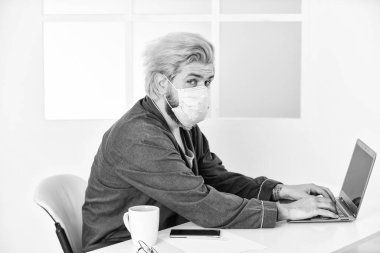 Uzaktan kumanda. Sınırlı hastalık yayılıyor. Uzaktan iletişim. Sosyal uzaklık. Çevrimiçi çalışan serbest çalışan bir adam. Adam internette sörf yaparken maske takıyor. Uzaktan kumanda. Çevrimiçi topluluk. Coronavirus karantinası