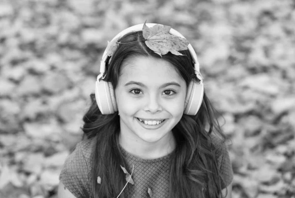 Conceito de dia do conhecimento. miúdo no parque de Outono. criança feliz relaxar nas folhas de outono. menina pequena usar fones de ouvido. de volta à escola. educação moderna. criança em floresta de outono — Fotografia de Stock