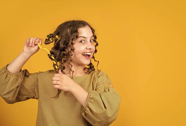 Güzel, sağlıklı saçlar. Parlak buklelerin tadını çıkarıyorum. Şekil vermek için yağ kremi. Kuaför malzemeleri. Moda ve güzellik. Küçük kız kuaför salonu. Küçük kıvırcık saçlı çocuk. Parti için saç stili