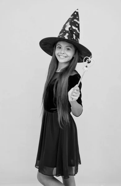 Gelukkig kind dragen heks hoed met toverstaf te creëren betovering op halloween, halloween magie — Stockfoto