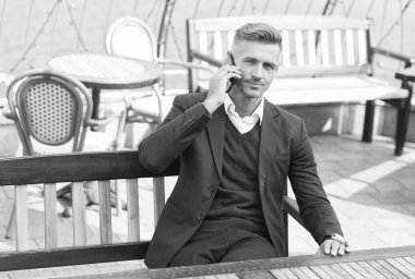 Resmi tarz konuşma işinde yakışıklı bir yönetici cep telefonu iletişiminde açık kafede dinleniyor, konuşuyor.