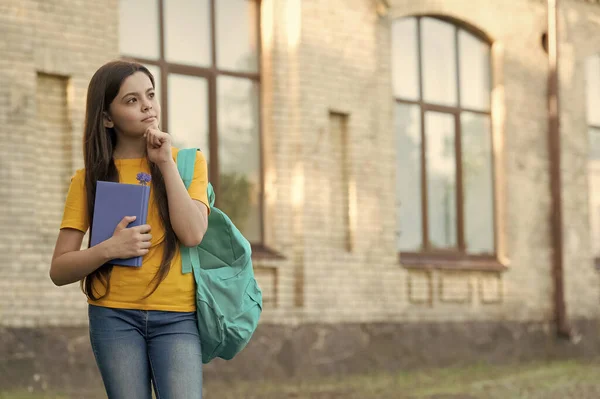 Malá holka přemýšlí venku. školské vzdělání v moderním životě. Zpátky do školy. dospívající dívka nosit batoh. notebook pro psaní vzpomínek. dítě se školním deníkem. Zamyšlená příručka pro děti. kopírovat prostor — Stock fotografie