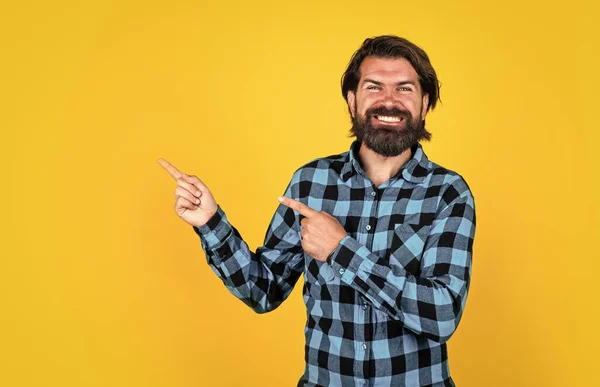 チェックされたシャツの幸せな残忍な男は長いひげを生やして指を指し、スペースをコピーし、広告 — ストック写真