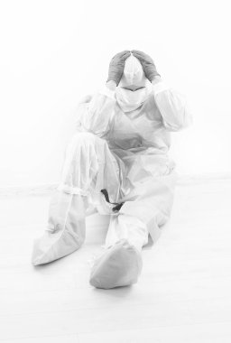 Erkek doktor epidemiyoloji uzmanının solunum maskesi ve koronavirüs pandemik karantinasındaki güvenlik önleyici kostümle korkunç bir baş ağrısı var. Beyaz, covid 19 semptomu var.