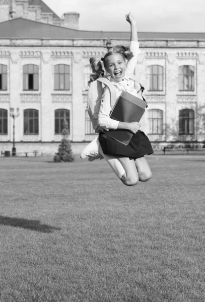 Freizeit. Energiegeladene Kinder springen auf dem Schulhof. Schulferien. Glückliche Schülerin in der Mitte. Abschlusstag. Grundschulbildung. Feiertage feiern. Sommerferien — Stockfoto